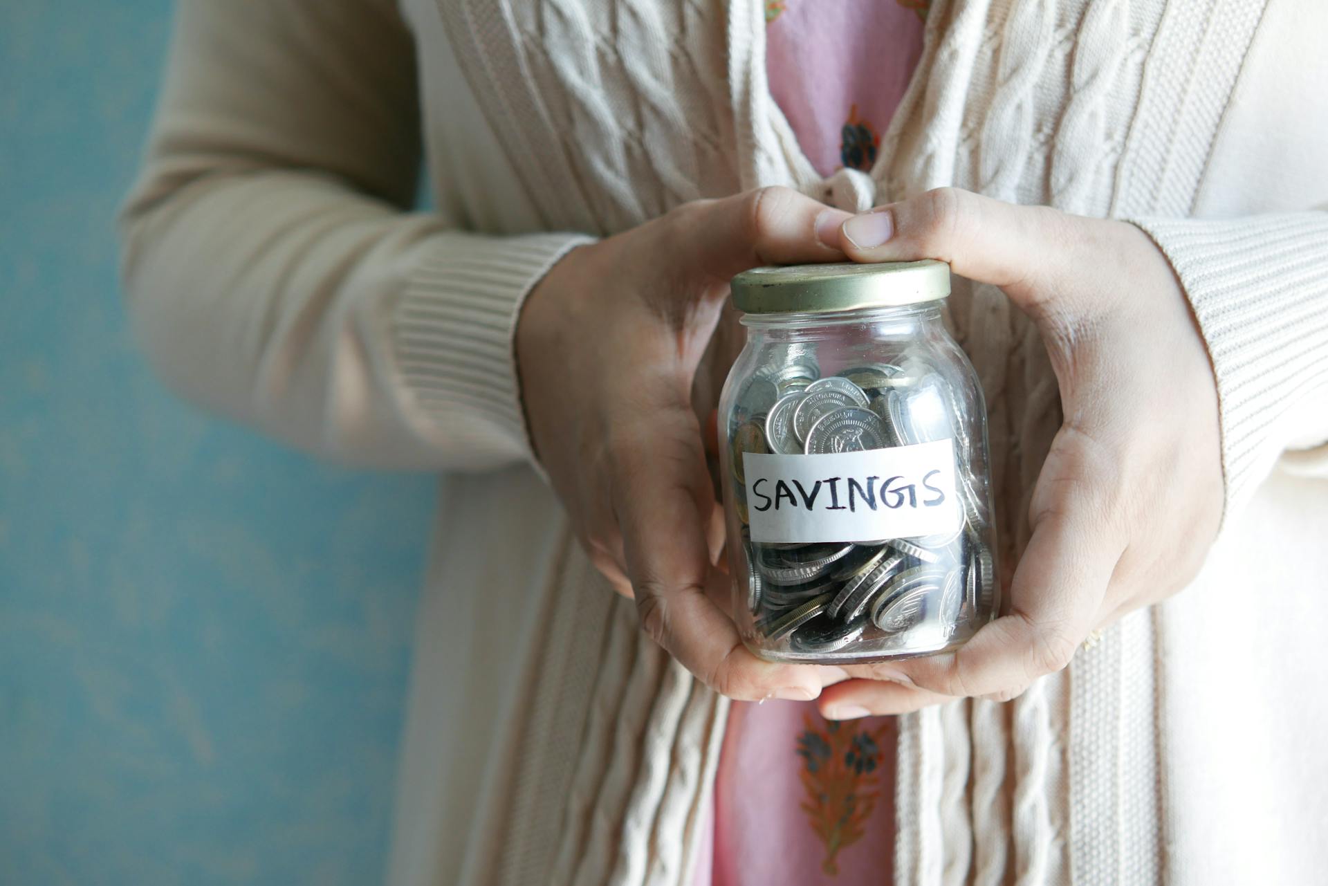 Person holding a savings jar — high yield savings accounts let your money grow passively