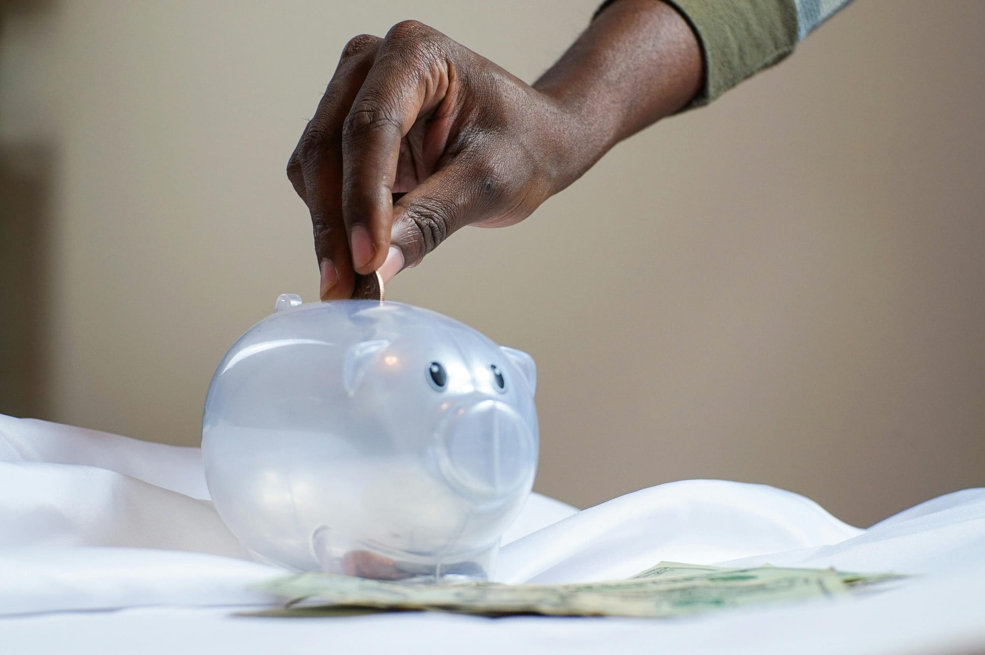 Close-up of a piggy bank with scattered coins on a wooden surface